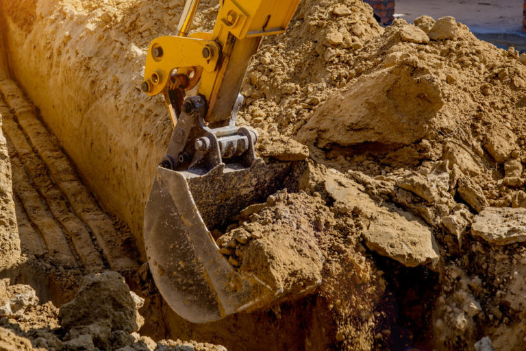 Working Excavator Tractor Digging A Trench At Construction Site.Close-up of a construction site excavator
